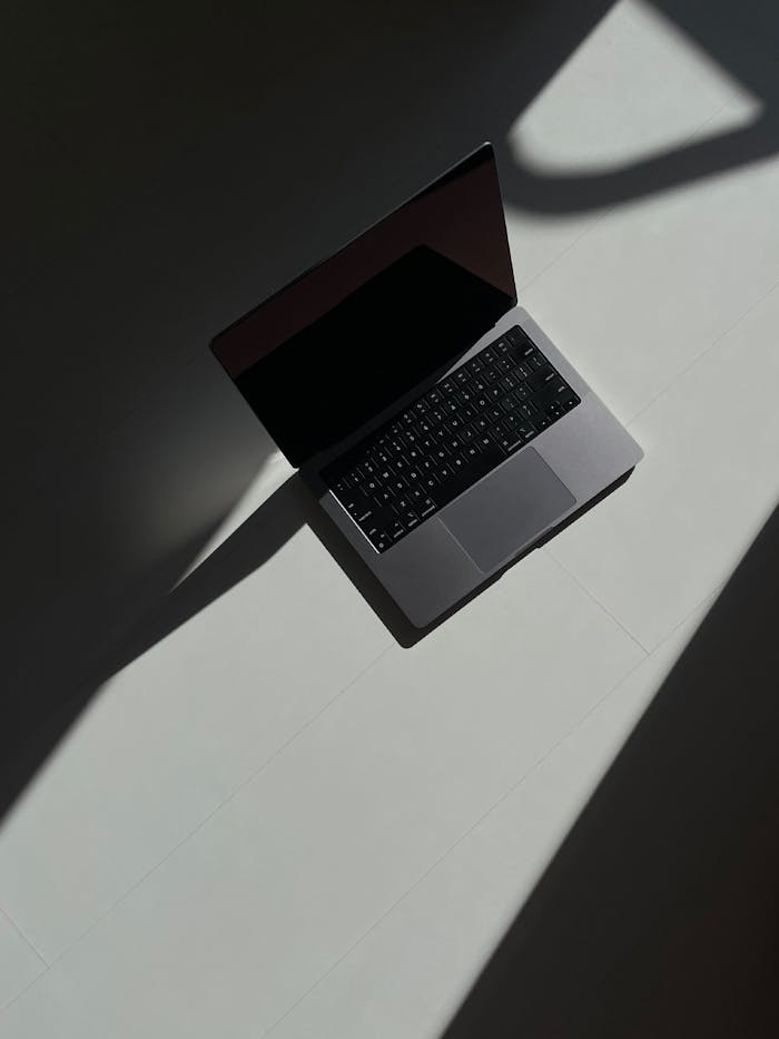 approach-img Artistic overhead view of an open laptop casting shadows on a flat surface.